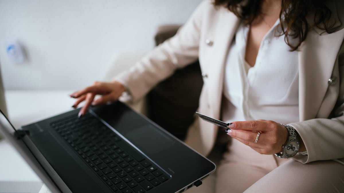 Persona realizando una compra online con una tarjeta y una computadora