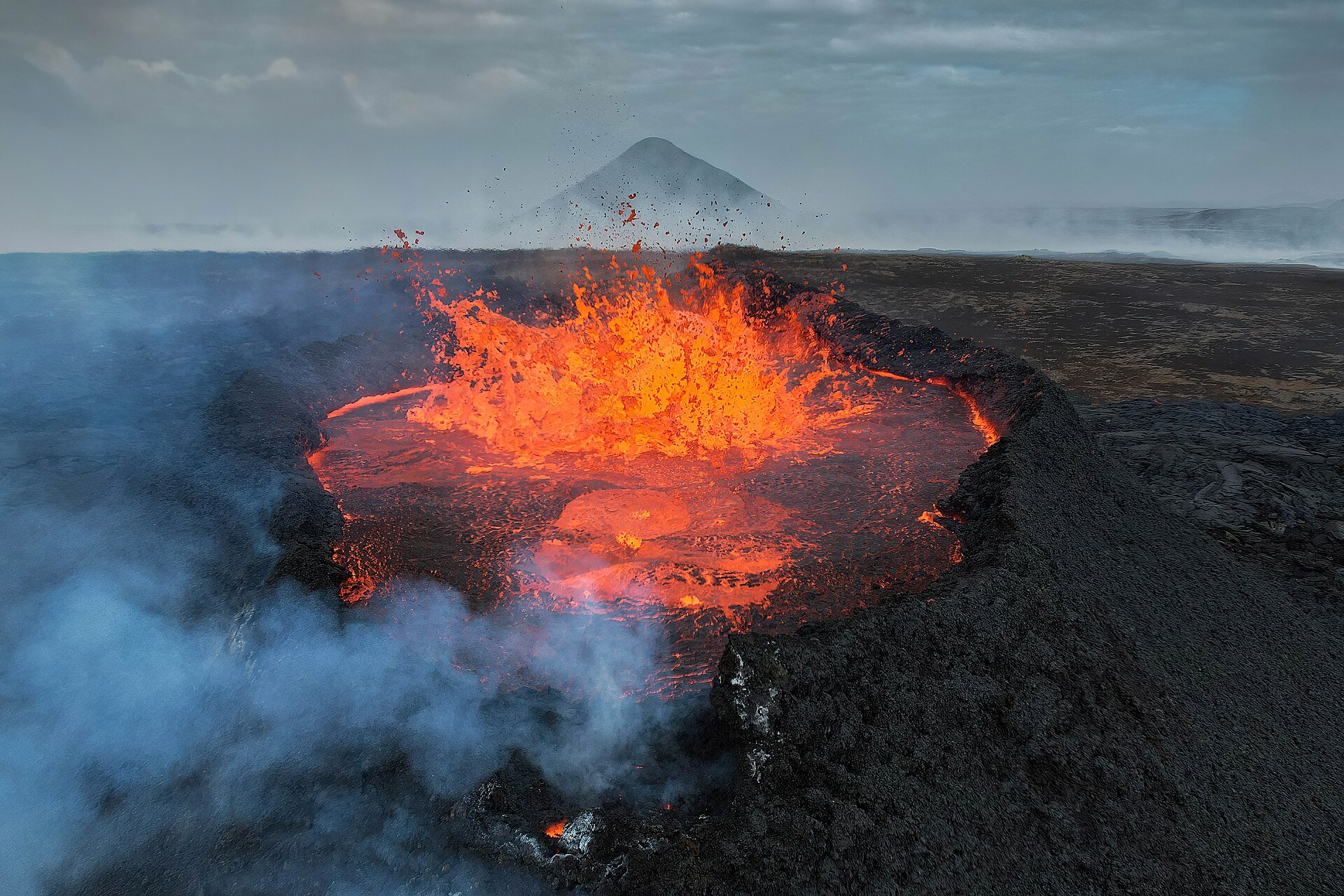 Lago de lava naranja dentro de un cráter volcánico oscuro