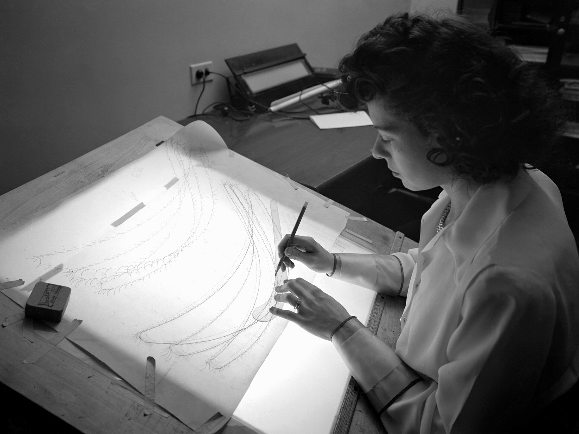 Investigadora trabaja sobre un plano técnico en una mesa iluminada