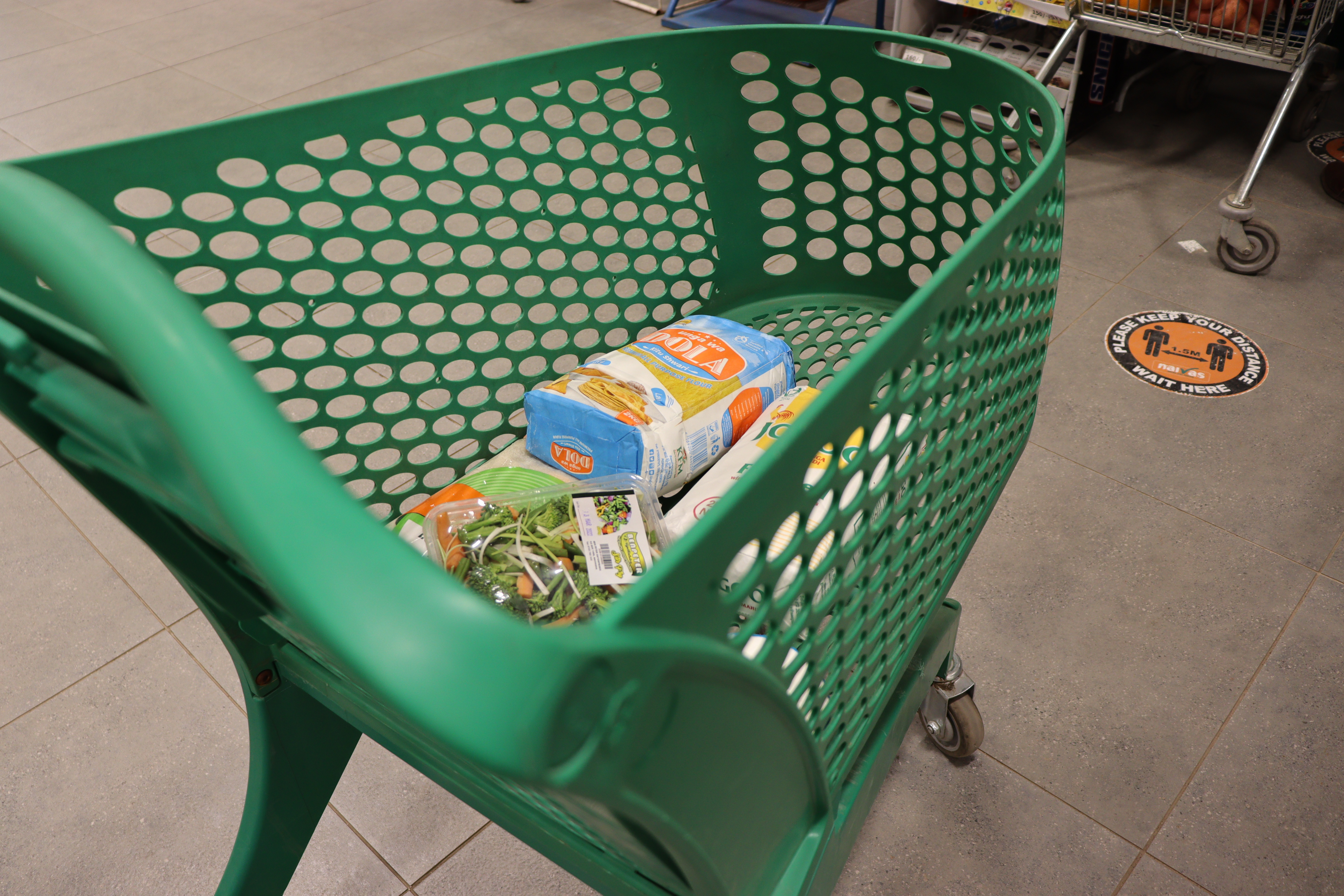 Carro de supermercado real frente a estantes con productos